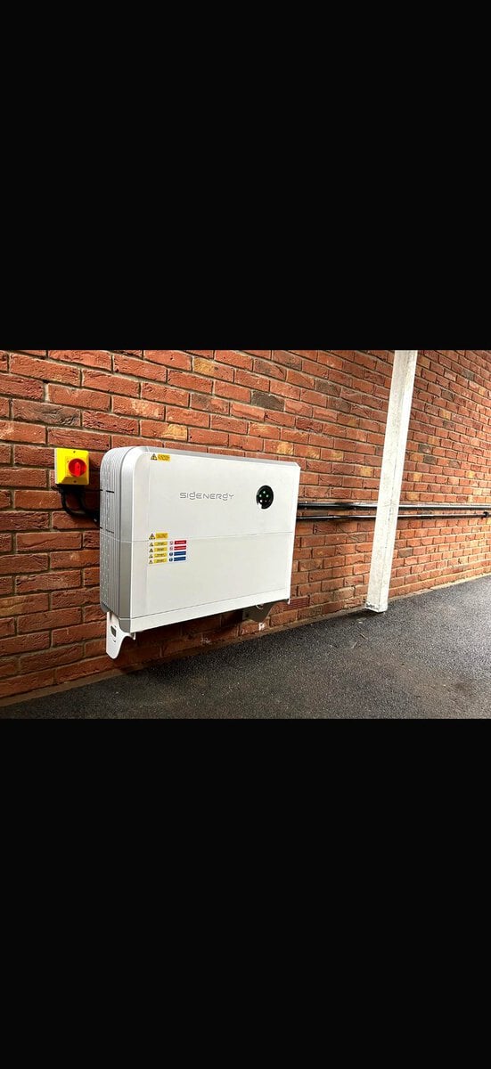Wall-mounted SigEnergy battery on red brick